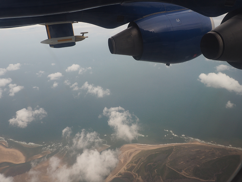 Blue sea below patchy white clouds, viewed from on board the FAAM aircraft