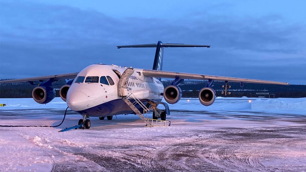 Large white and blue aircraft stationary on a snowy runway.