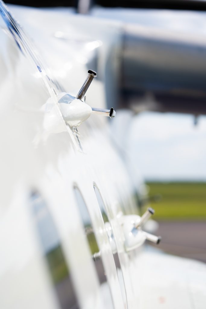 Silver probe mounted on side of blue and white research aircraft.