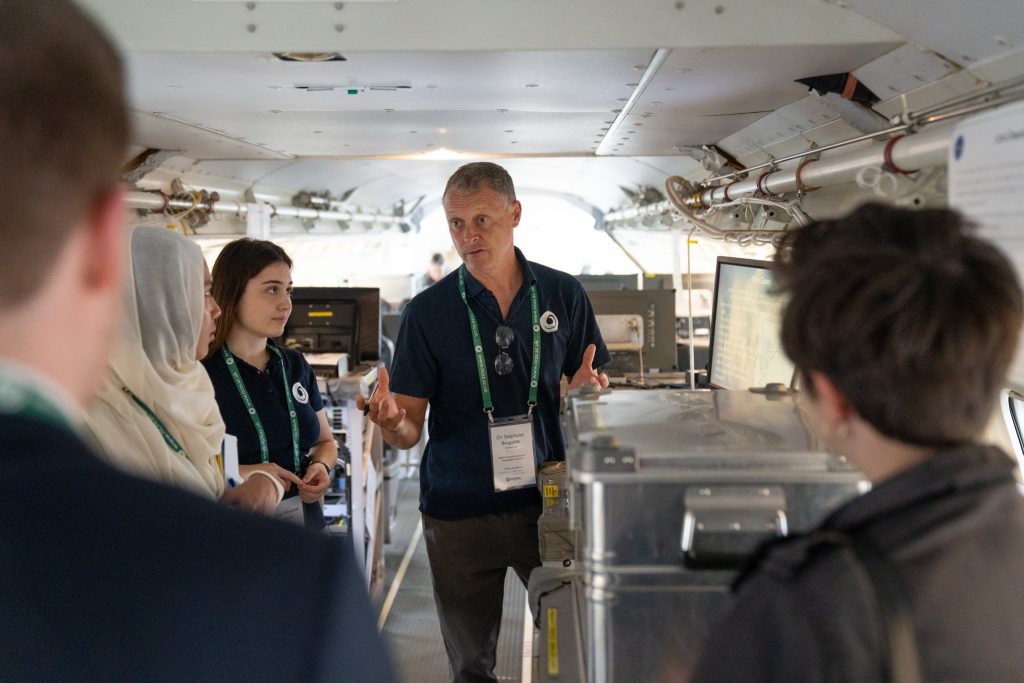 Five people stood inside research aircraft. One person is talking to the rest of the group.